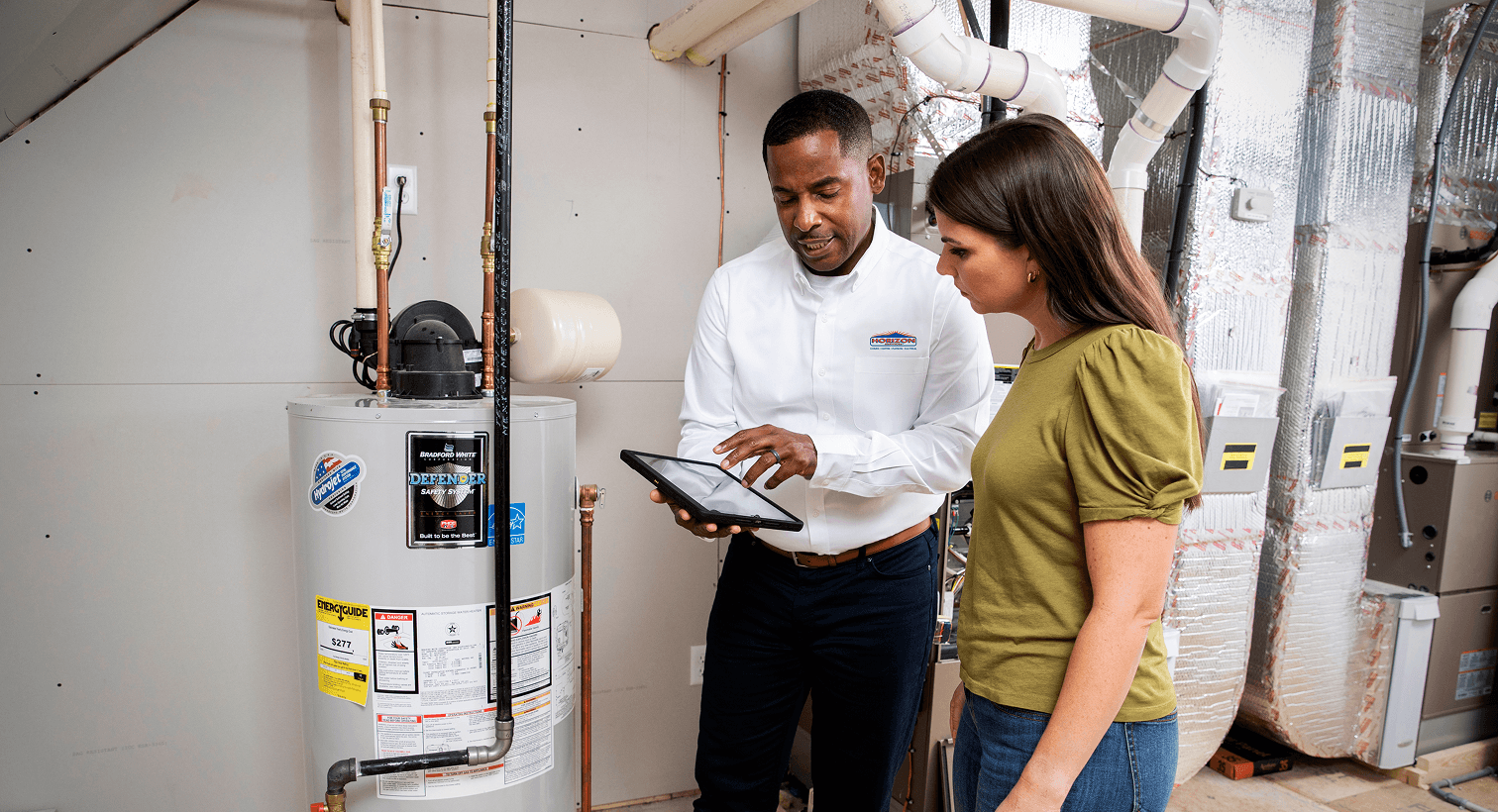 Technician and woman looking at a tablet next to a water heater