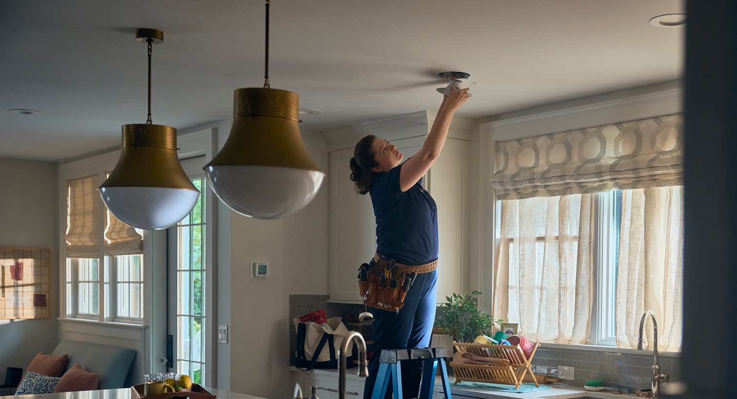 Horizon electrician installing a ceiling-mounted light fixture in a residential kitchen